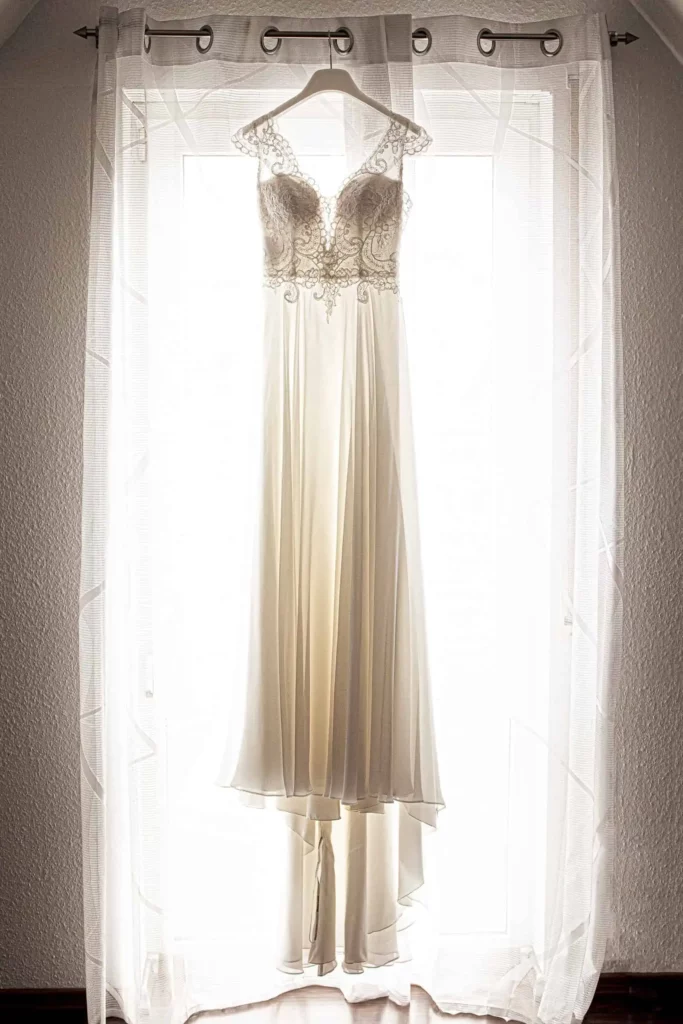 Brautkleid hängt vor Fenster in Freudenstadt, festgehalten vom Hochzeitsfotograf beim Getting Ready.