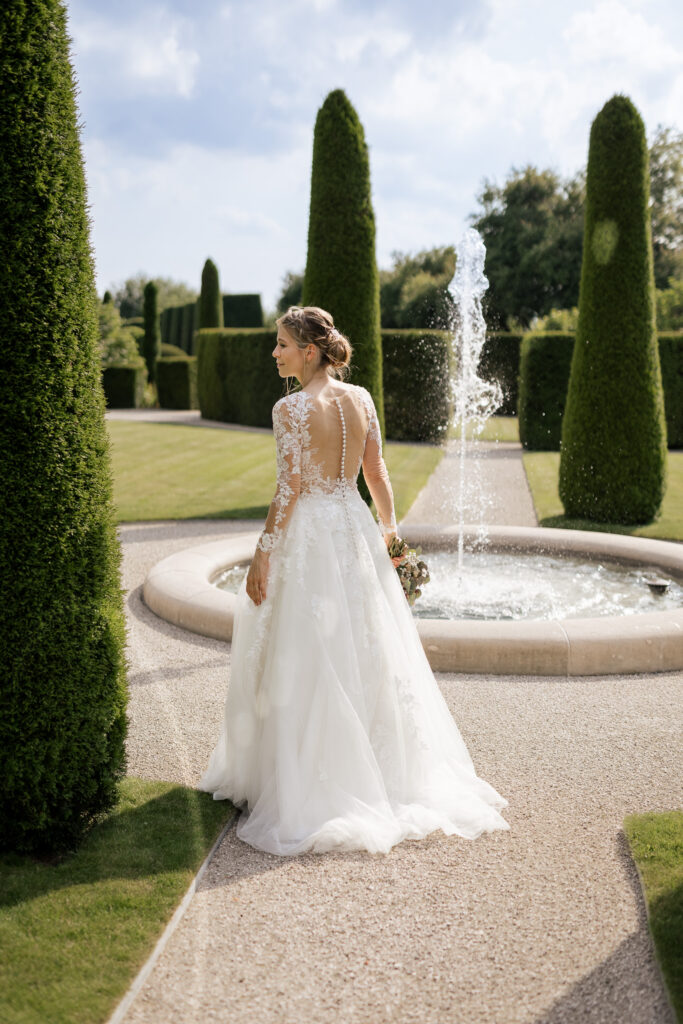 Braut im eleganten Kleid am Brunnen bei stilvoller Gartenhochzeit in Böblingen