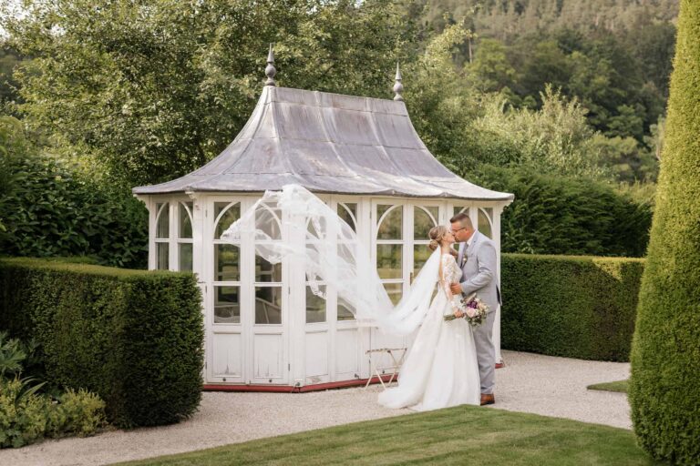 Kuss im Garten vor Pavillon – natürliche Hochzeitsfotos mit romantischem Flair